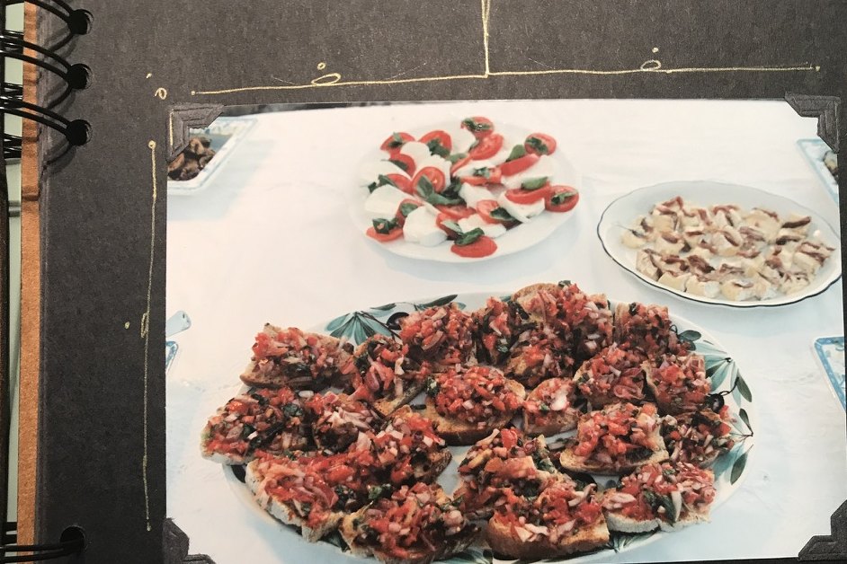 A platter of bruschetta and other antipasti on a white table.